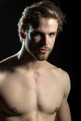 Fototapeta premium Naked man looking at the camera on black background in the studio closeup. Handsome man
