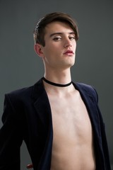 Androgynous man in blazer posing against grey background