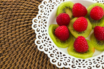 Fresh Red Raspberries on a white artistic plate / Red Fresh Raspberries on a white artistic plate with cookies, rosemary, chocolate and cream in the background.