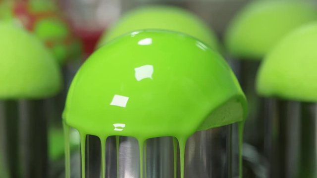 Green glaze flows to the cake. Drops of glossy liquid glaze drain from the cake close up
