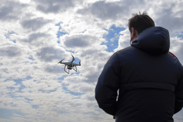 A man with a remote control in his hands. Controlling the flight of the drone against the sky. Phantom.