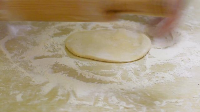Making a dough for home pizza. The girl rolls the dough on a table with flour. Full hd video quality