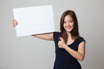 Fototapeta na wymiar Young Asian woman show thumbs up with white blank sign.
