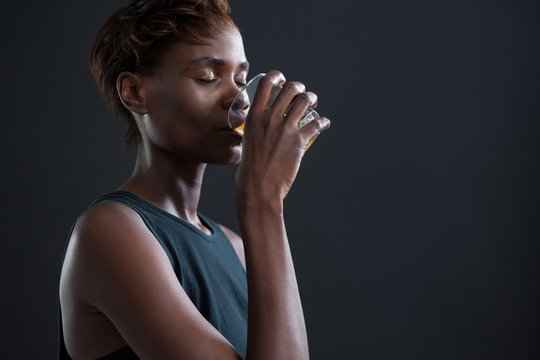 Androgynous man drinking whiskey from glass