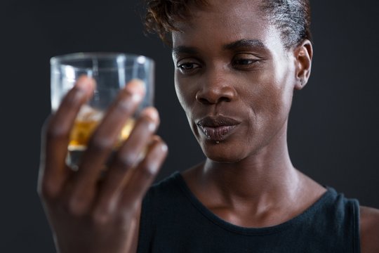 Androgynous man holding whiskey glass