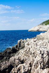 Beautiful summer view on white stone shore of an island and blue see or ocean and sky full of bright sunlight as relaxation and vacation Mediterranean background