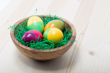  Four hand painted easter eggs on a wood bowl on a pine wood table
