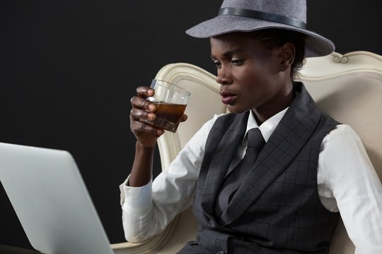Androgynous man drinking whiskey while sitting on a chair