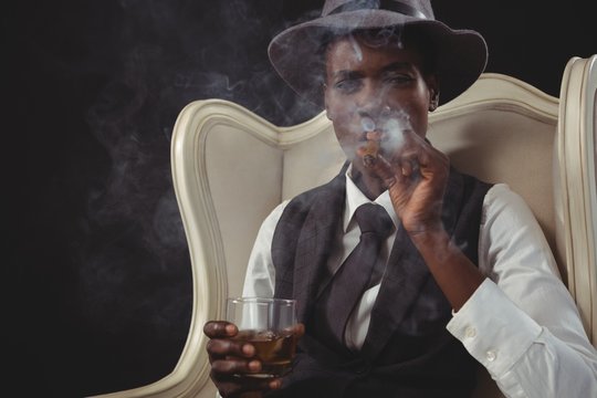 Androgynous man smoking cigar while while sitting on a chair - Powered by Adobe