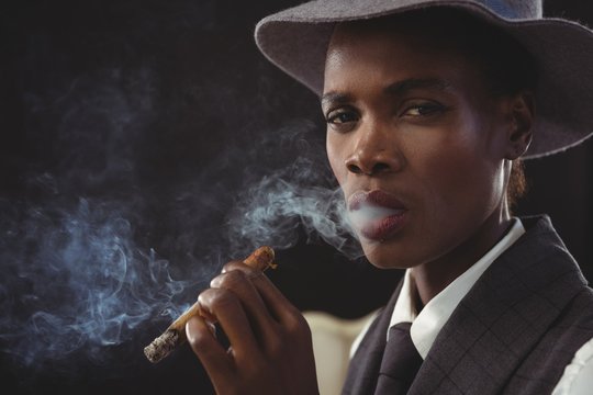 Androgynous man smoking cigar while sitting on a chair