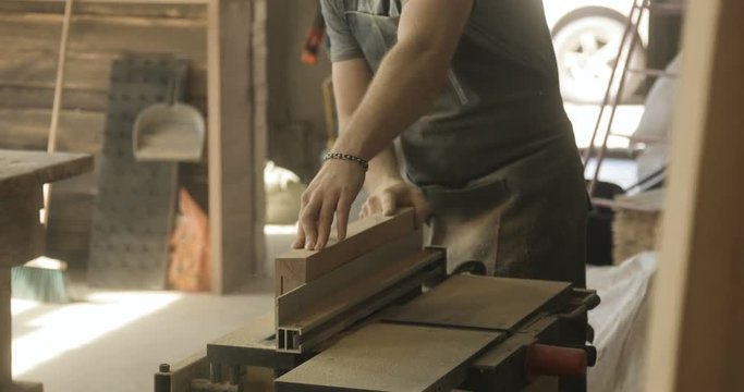man cutting boards with electric saw, in a carpentry workshop