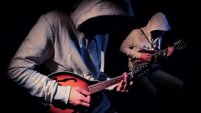 Anonymous Hooded Mandolin Players on Black Background