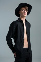 Androgynous man in hat posing with hands in his back pocket