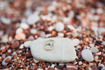 Wedding rings of newlyweds on beach pebbles. Engagement gold rings. Wedding in Montenegro.