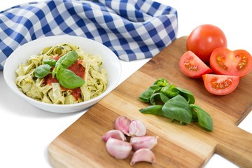 Vegetables on cutting board by pasta and napkin