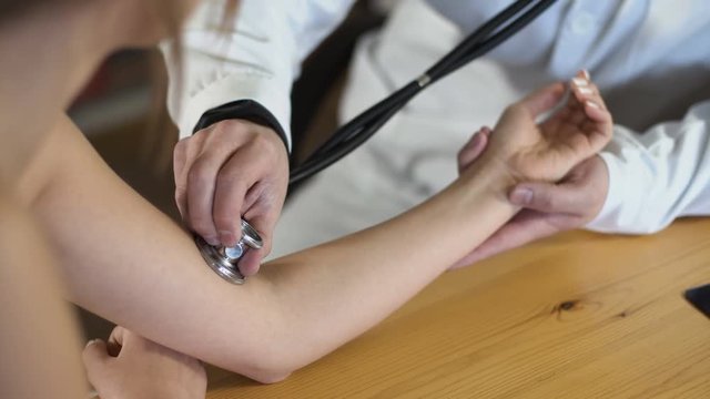 close up of a male doctor hands is measuring pulse with stethoscope 4k