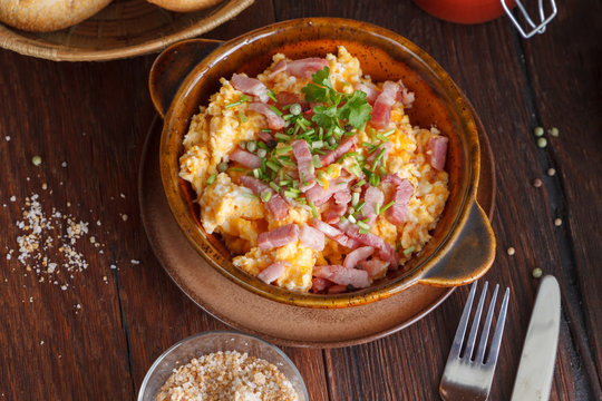 scrambled eggs with bacon on a wooden background