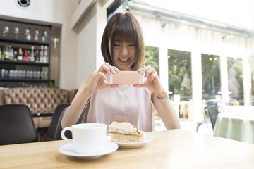 A young lady is shooting a cake with a smartphone