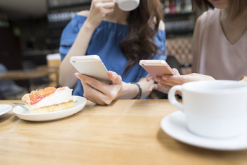 Two women are watching a smartphone at a cafe