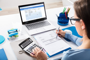 Businesswoman Calculating Invoice Using Calculator