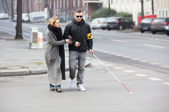 Woman Assisting Blind Man On Street