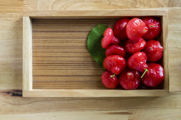 Rose Apples fruits in wooden tray. On a wooden table. Free space for text . Top view