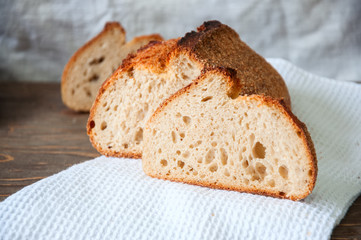 Close up of freshly baked sourdough whole wheat flour bread loaf on a white napkin. Copy space.