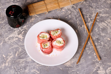 Finger food. Rolls of salmon with cream cheese close-up on the table horizontal
