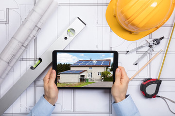 An Architect Using Digital Tablet On Blueprint