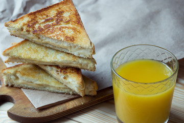 Cheese toasts for breakfast and orange juice in glass. Sandwich for a breakfast