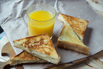 Cheese toasts for breakfast and orange juice in glass. Sandwich for a breakfast