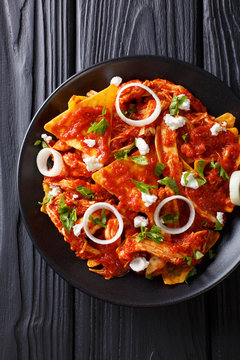 Hot Mexican food chilaquiles with chicken close-up on a plate. Vertical top view