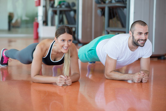 Gym man and woman push-up strength pushup with dumbbell in a workout