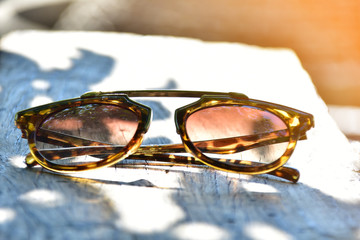 sunglasses on wooden table at sunny day.