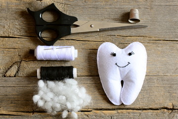 Obraz premium Making a felt tooth fairy. Step. Tutorial. Stuffed felt tooth fairy toy, scissors, thread, thimble, needle, filler on vintage wooden table. Simple and fun sewing crafts for kids. Top view. Closeup