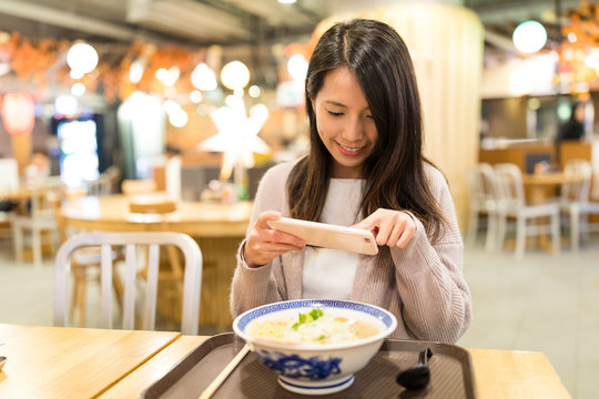 Woman taking photo in her ramen in restaurant