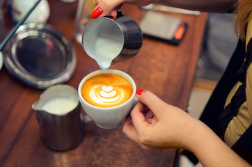 Barista pours gentle whipped milk into the cup for the fragrant cappuccino.