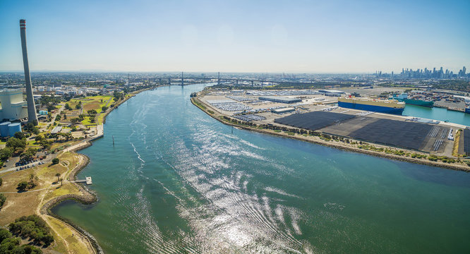 Aerial panoramic view of Newport Power Station, West Gate Bridge, Yarra River, and large car carriers ships at high noon. Melbourne, Victoria, Australia.