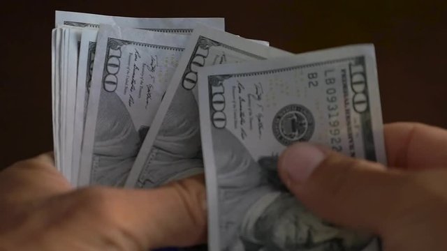 Slow Motion Close-up of a businessman hands counting hundred dollar bill
