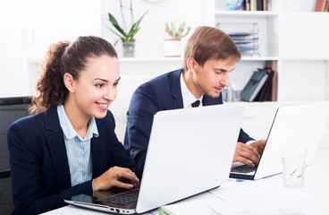 Obraz premium Two office workers work using laptops