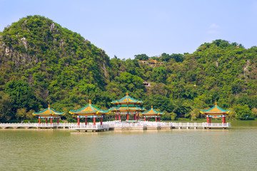 Fototapeta na wymiar Complex of pavilion with traditional Chinese roofs on lake background mountain