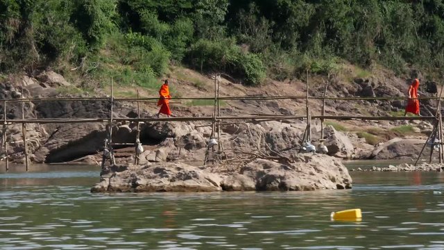 Monks crossing an old bamboo bridge across the River in Luang Prabang Laos