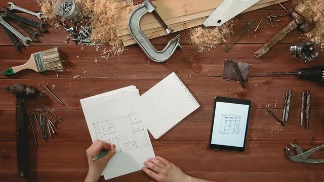 Top view craftsman hands drawing a sketch of floor plan on paper using digital tablet
