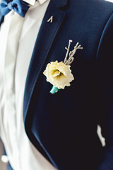 Details of male wedding clothes. Beautiful boutonniere pinned on man in blue suit, white shirt and...