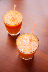 Lemon and orange smoothies on the table with slices of lemon and orange in a glass cups with tubes