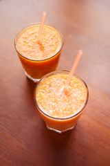 Lemon and orange smoothies on the table with slices of lemon and orange in a glass cups with tubes