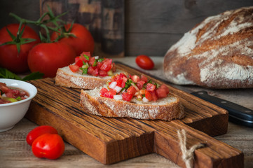 Tomato salsa sauce on slices of bread served on a wooden board. Rustic style and close up.