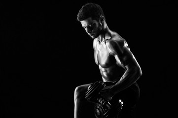 Young determined sportsman working out shirtless showing off his strong muscular body lifting weights copyspace monochrome shot dumbbells equipment gym fitness sport motivation biceps concept.