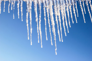 Icy icicles on blue sky background