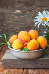 Close up of fresh ripe velvet mellow honeyed peaches  with leaves and water drops in a vintage bowl on a wooden board. Summer fruits concept. Rustic style.
